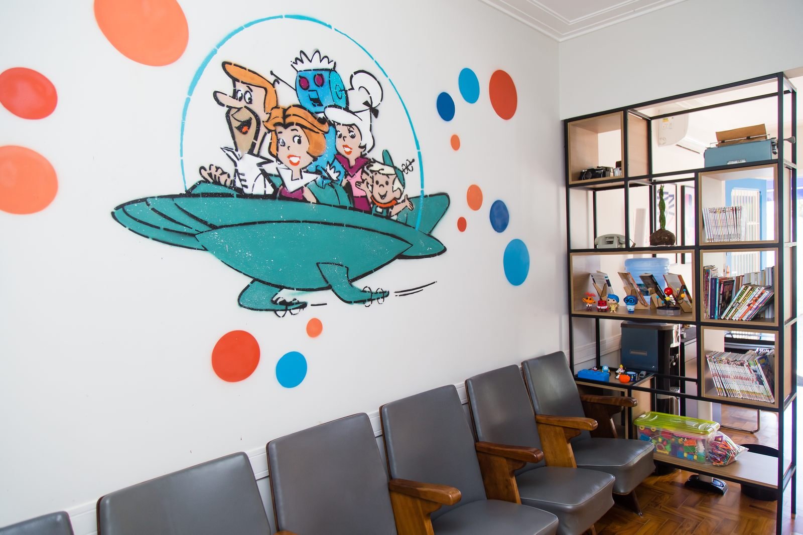 Sala de espera do NPAS, com cadeiras, estante de brinquedos e mural pintado