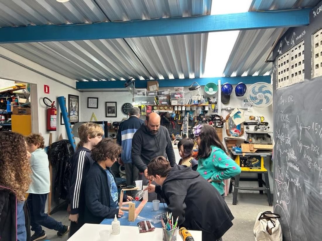 Crianças e tutor trabalhando juntos no espaço maker coberto do NPAS