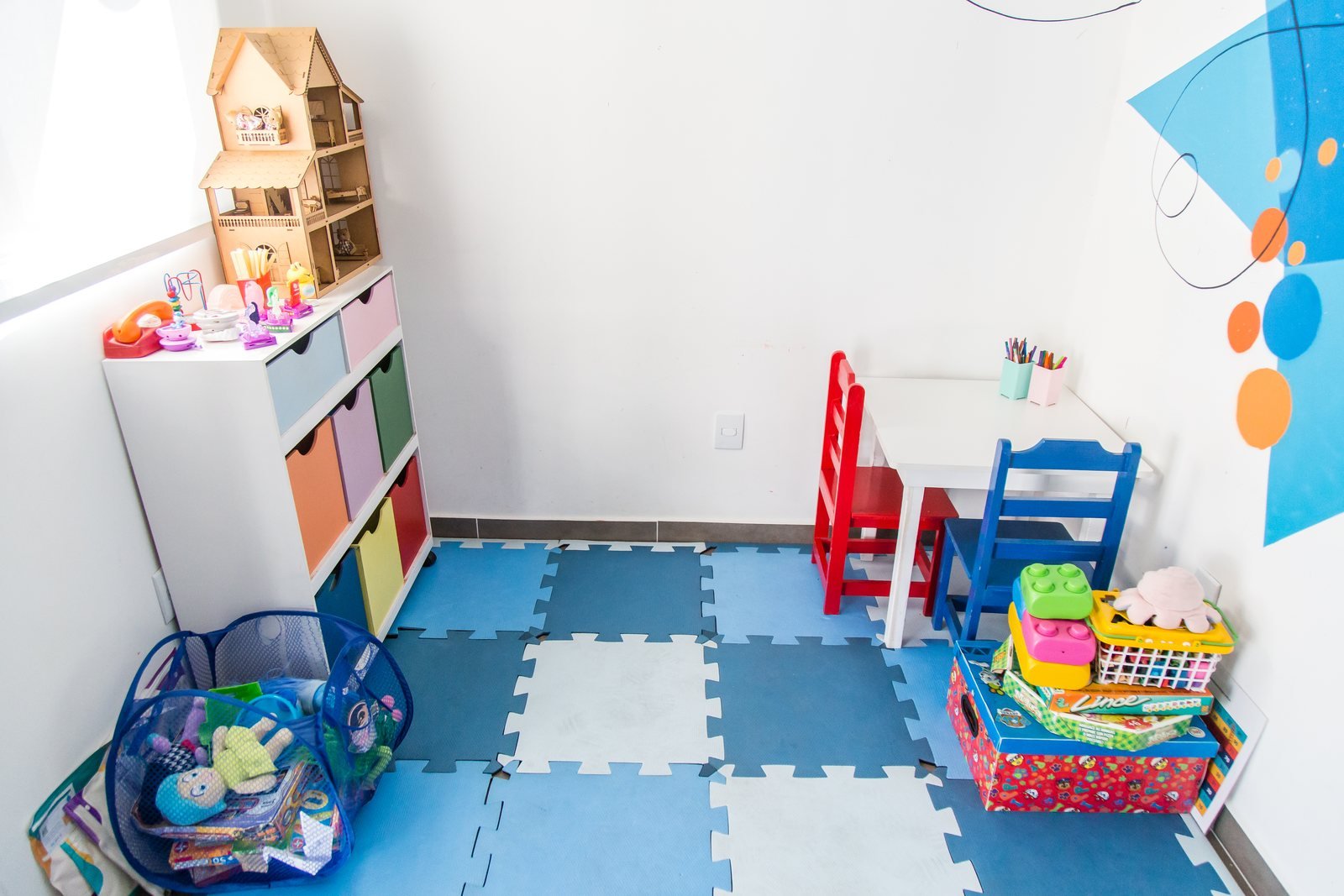 Sala de atendimento infantil do NPAS, com tapete de encaixar, casinha de bonecas e brinquedos